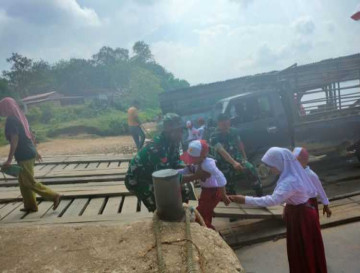 Tim Satgas TMMD Bantu Anak Sekolah Menyeberangi Sungai